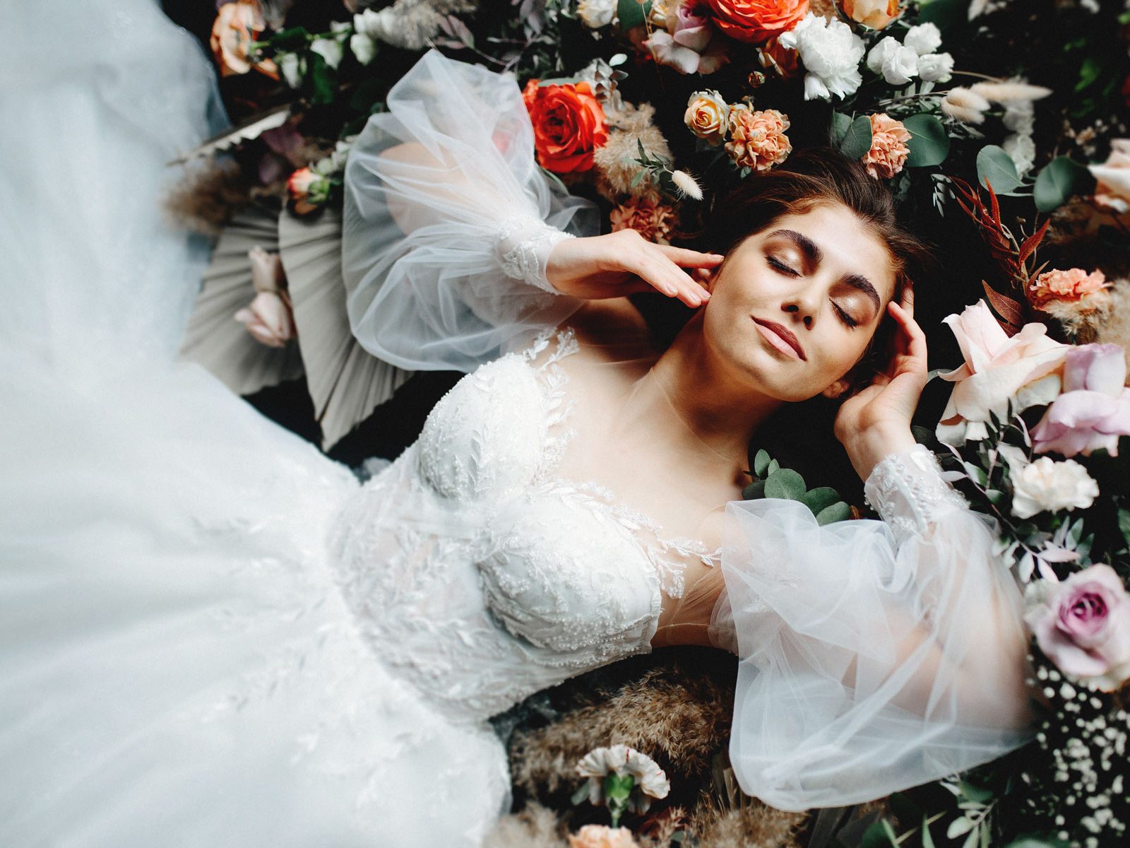 Beautiful bride lies on the floor in flowers in a wedding dress